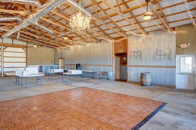 miscellaneous room featuring wood walls, a high ceiling, and a notable chandelier