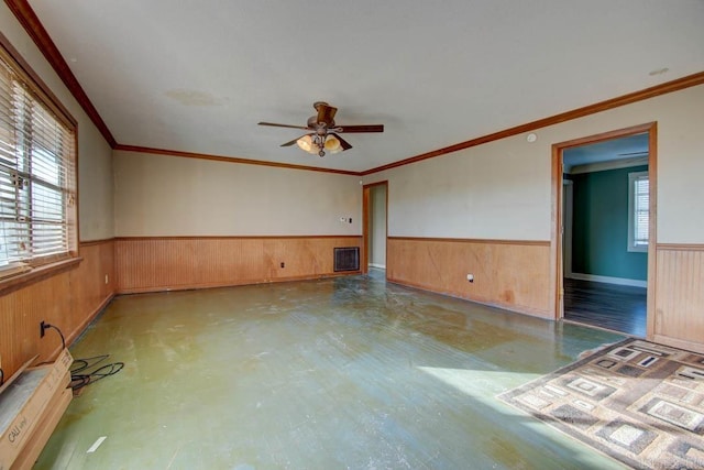 spare room featuring ornamental molding, ceiling fan, and wooden walls