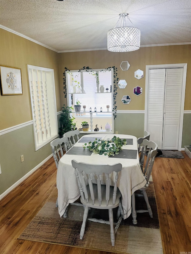 dining room featuring crown molding, a textured ceiling, baseboards, and wood finished floors
