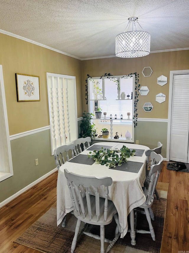 dining area featuring ornamental molding, a textured ceiling, baseboards, and wood finished floors