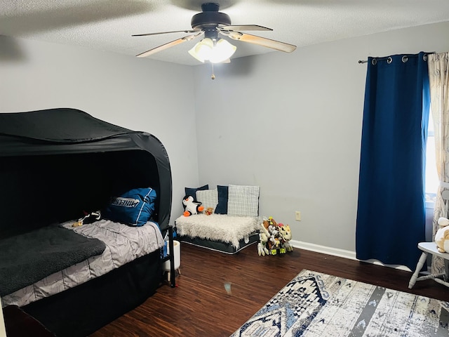 bedroom with a ceiling fan, a textured ceiling, baseboards, and wood finished floors
