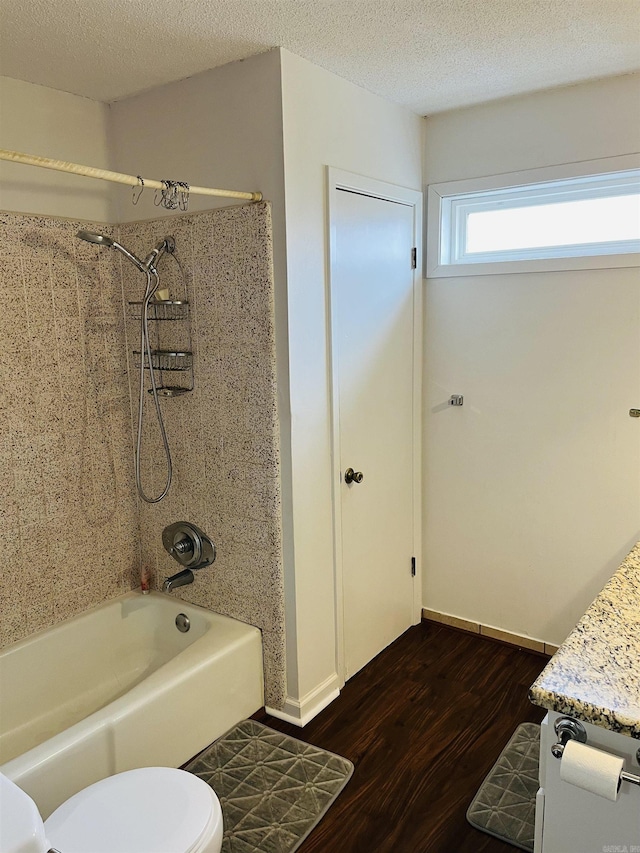 full bathroom featuring baseboards, toilet, wood finished floors, a textured ceiling, and shower / washtub combination