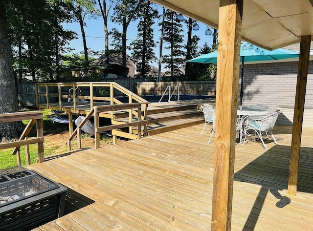 view of dock with a deck, an outdoor fire pit, and a fenced backyard
