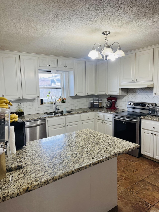 kitchen with tasteful backsplash, white cabinets, appliances with stainless steel finishes, under cabinet range hood, and a sink