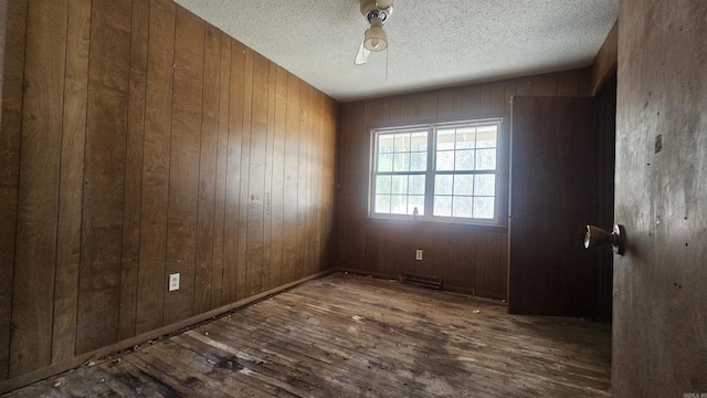 10085 James Dr, Havana, AR 72842 - empty room featuring wooden walls, dark wood-type flooring, and a textured ceiling