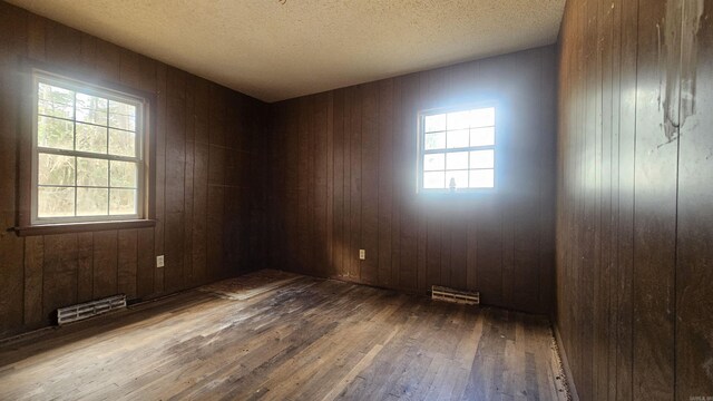 10085 James Dr, Havana, AR 72842 - unfurnished room with a textured ceiling, dark wood-type flooring, and wooden walls
