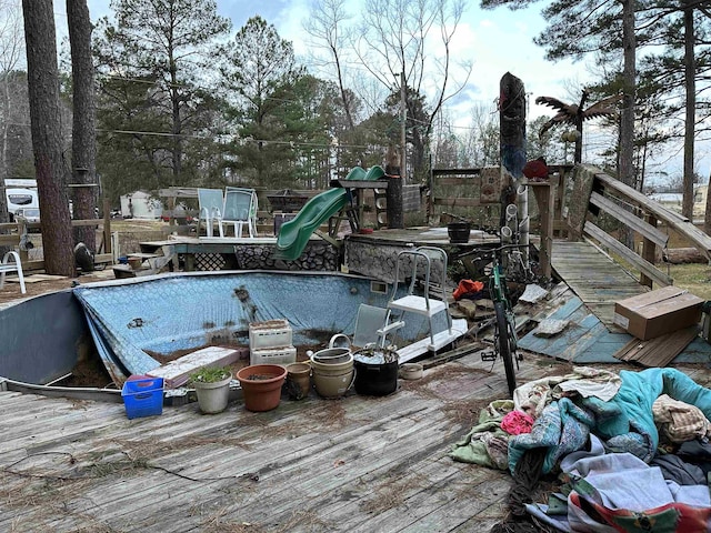 view of swimming pool featuring a wooden deck and a playground