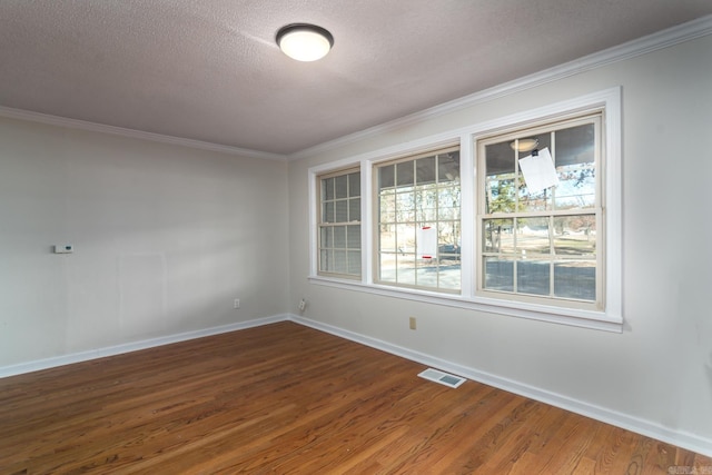 spare room with a textured ceiling, plenty of natural light, crown molding, and hardwood / wood-style floors