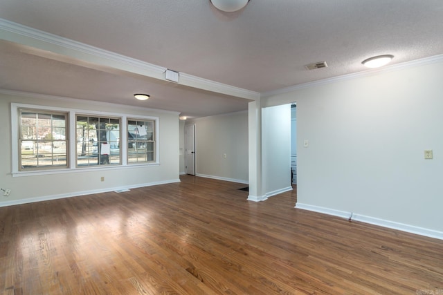 empty room with crown molding, dark wood-type flooring, and a textured ceiling