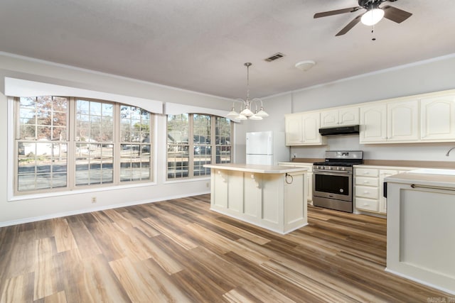 kitchen with hanging light fixtures, white cabinets, stainless steel range oven, a kitchen island, and white fridge