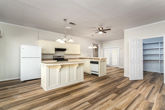 kitchen featuring sink, white cabinetry, white appliances, a center island, and a textured ceiling