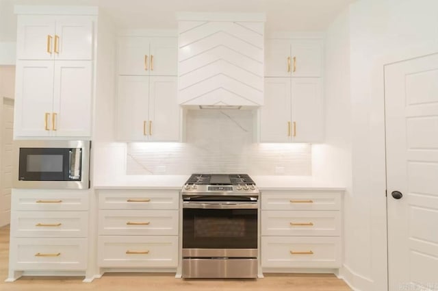 kitchen featuring decorative backsplash, white cabinetry, stainless steel appliances, and light hardwood / wood-style floors