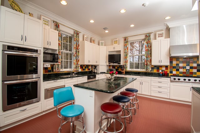 kitchen featuring dark colored carpet, wall chimney exhaust hood, a center island, double oven, and backsplash