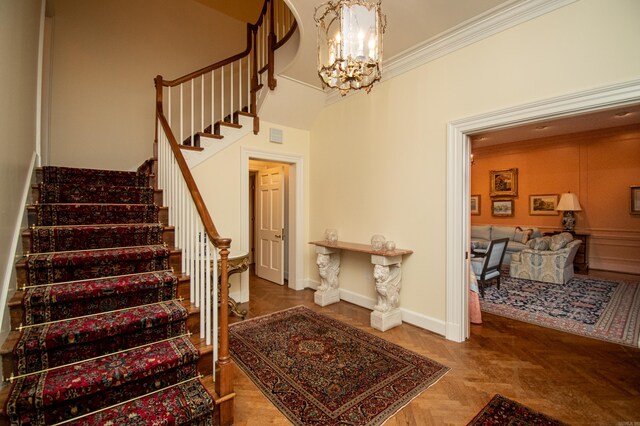 stairway featuring a notable chandelier, ornamental molding, a towering ceiling, and parquet flooring