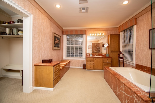 bathroom featuring ornamental molding, vanity, and tiled bath