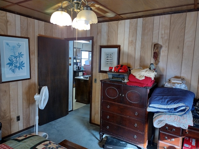 carpeted bedroom with wood walls and ceiling fan with notable chandelier