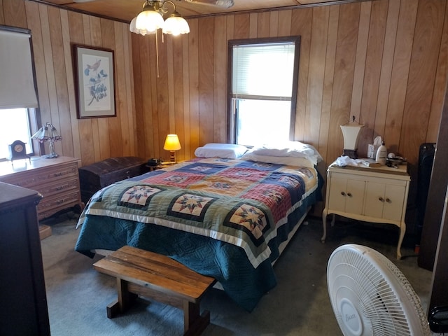 bedroom with wood walls, ceiling fan, and dark colored carpet