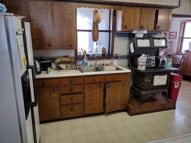 kitchen with light tile flooring, white fridge, and sink