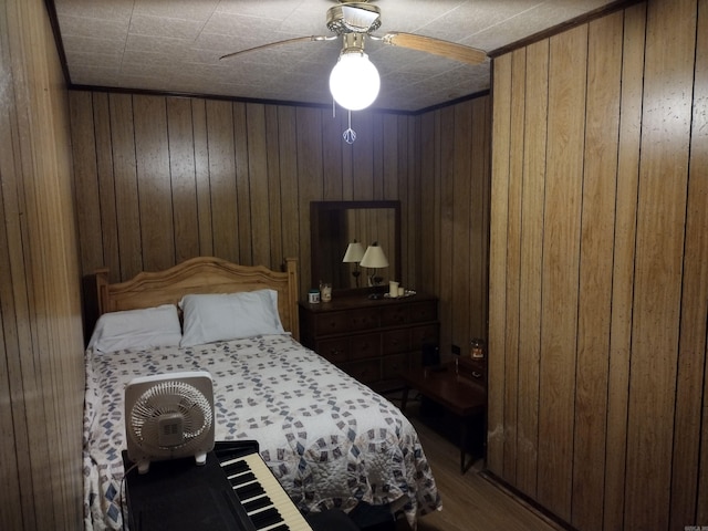 bedroom with ceiling fan and wood walls