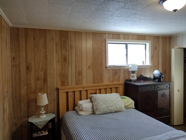 bedroom featuring wooden walls and crown molding