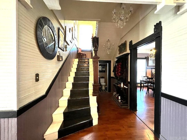 staircase featuring dark wood-type flooring and a chandelier