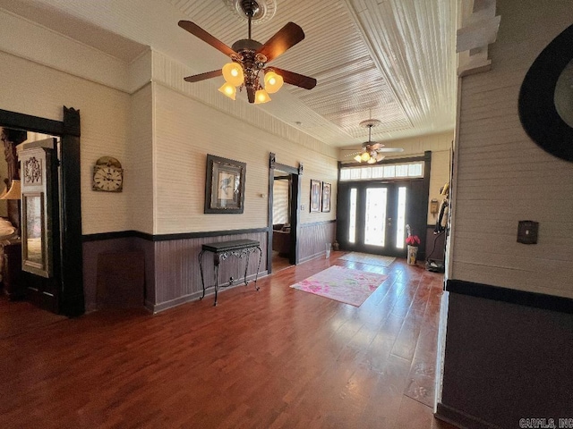 entrance foyer with a barn door, ceiling fan, dark wood-type flooring, and french doors