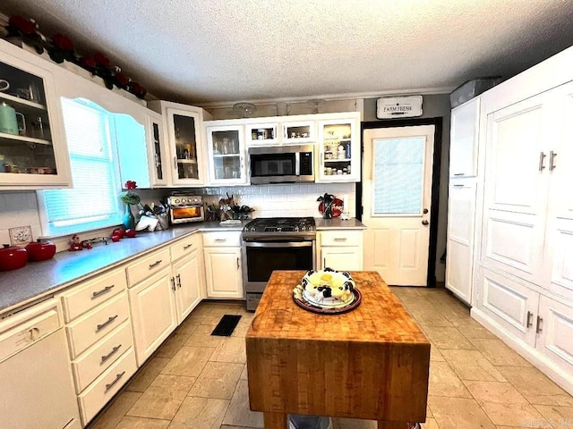 kitchen featuring a center island, wooden counters, stainless steel appliances, and light tile floors