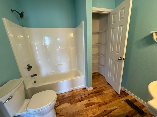 bathroom featuring toilet, bathing tub / shower combination, and hardwood / wood-style floors