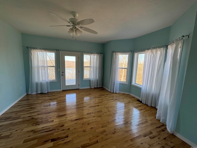 empty room featuring light hardwood / wood-style floors, ceiling fan, and a wealth of natural light