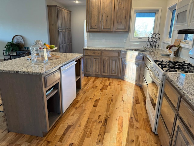 kitchen with a kitchen island, light hardwood / wood-style floors, white appliances, and light stone counters