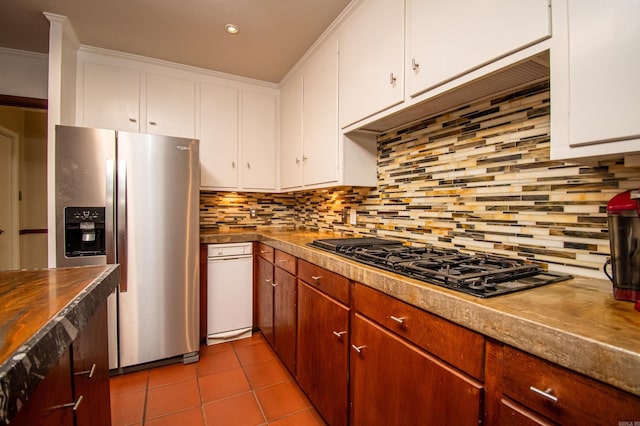 kitchen featuring stainless steel fridge, tasteful backsplash, gas stovetop, tile floors, and white cabinetry