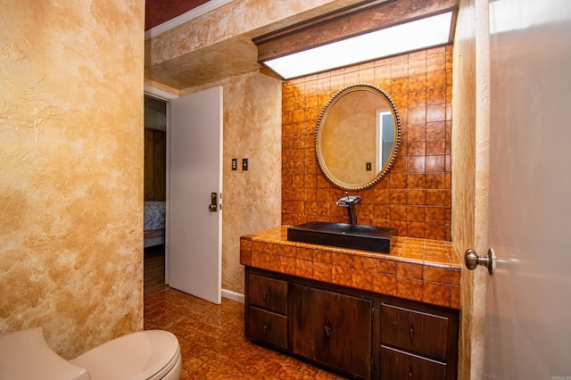 bathroom featuring tile flooring, tile walls, toilet, and vanity