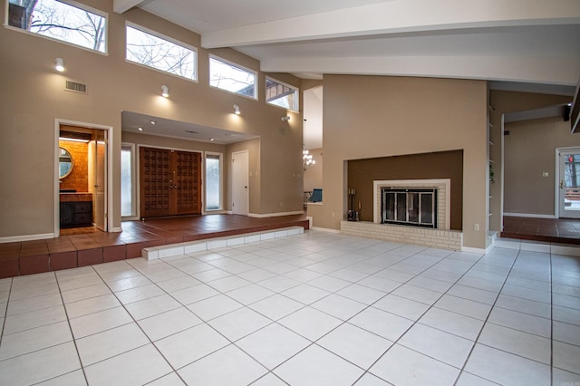 unfurnished living room featuring high vaulted ceiling, beamed ceiling, and light tile floors