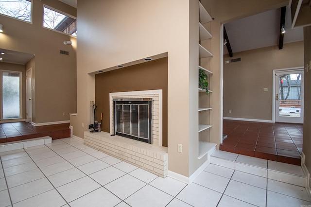 unfurnished living room featuring built in features, a brick fireplace, and light tile floors