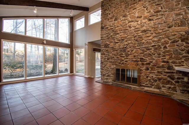 unfurnished living room with tile floors, beam ceiling, a healthy amount of sunlight, and a fireplace