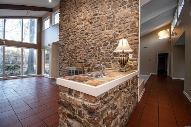 interior space featuring dark tile flooring, beam ceiling, a healthy amount of sunlight, and sink