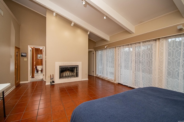 unfurnished bedroom with vaulted ceiling with beams, dark tile flooring, and ensuite bath