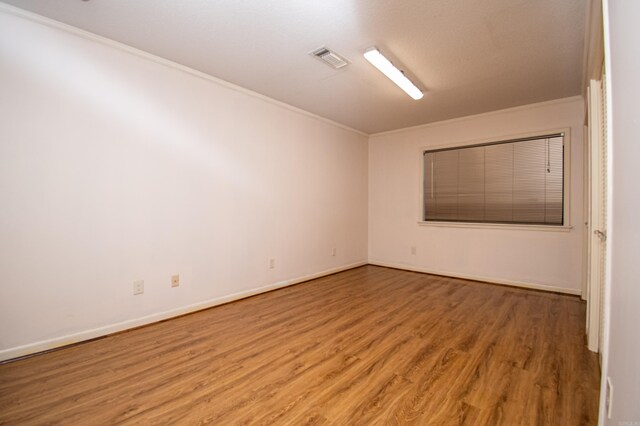 spare room featuring ornamental molding and hardwood / wood-style flooring