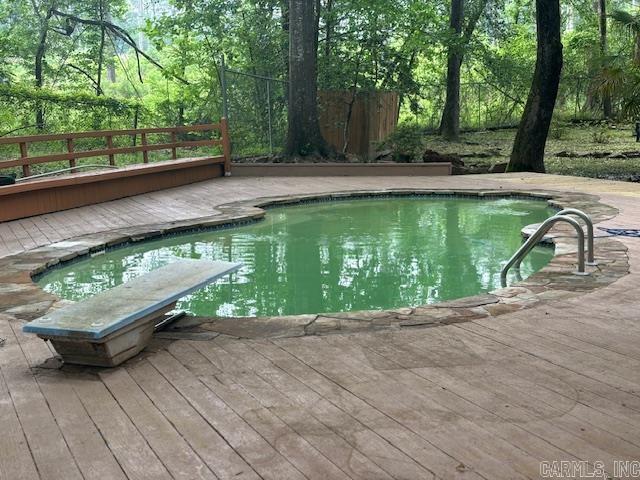 view of swimming pool with a diving board and a wooden deck