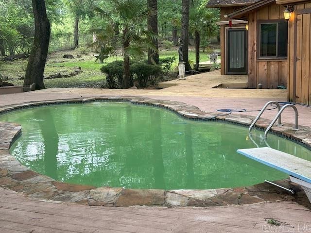 view of swimming pool featuring a diving board