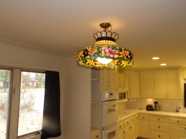 kitchen with decorative light fixtures, crown molding, white appliances, and white cabinetry