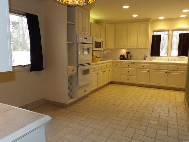 kitchen with backsplash, white appliances, and sink