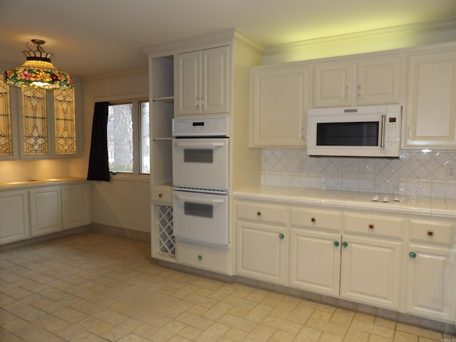 kitchen featuring decorative backsplash, white appliances, pendant lighting, tile counters, and ornamental molding