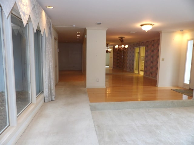 empty room featuring an inviting chandelier, light hardwood / wood-style flooring, and ornamental molding