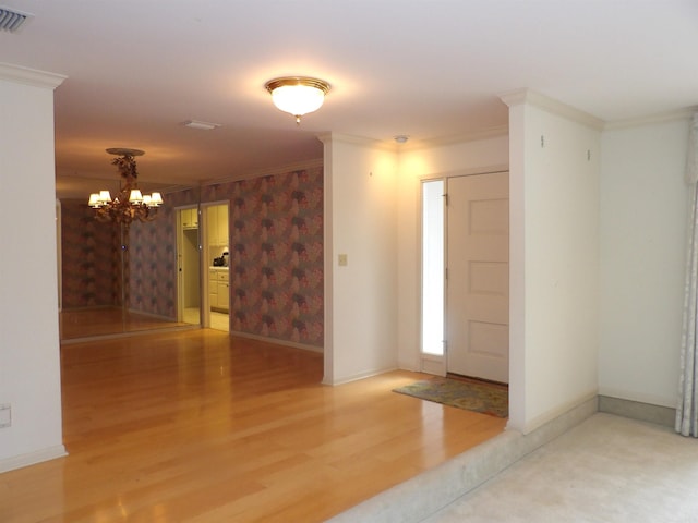 entrance foyer featuring an inviting chandelier, crown molding, and hardwood / wood-style floors