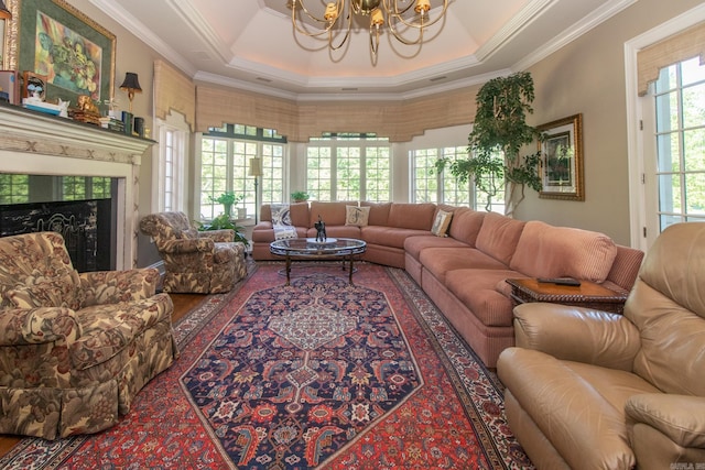 living room with ornamental molding, a chandelier, a tray ceiling, and wood-type flooring