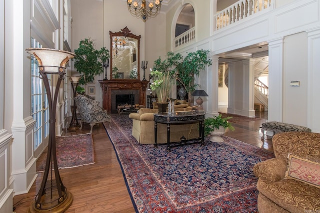 interior space featuring a notable chandelier, ornate columns, a high ceiling, and wood-type flooring