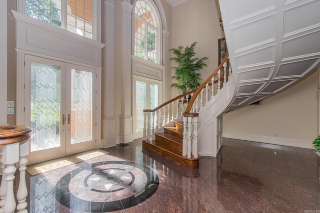 foyer with dark tile floors, french doors, and a towering ceiling