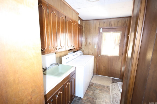 washroom with cabinets, wooden walls, dark tile floors, independent washer and dryer, and sink