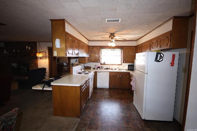 kitchen featuring ceiling fan, white appliances, range hood, brick wall, and a brick fireplace